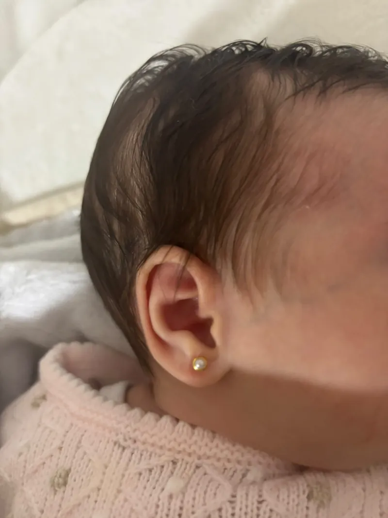 Pendiente de oro en la oreja de una bebé