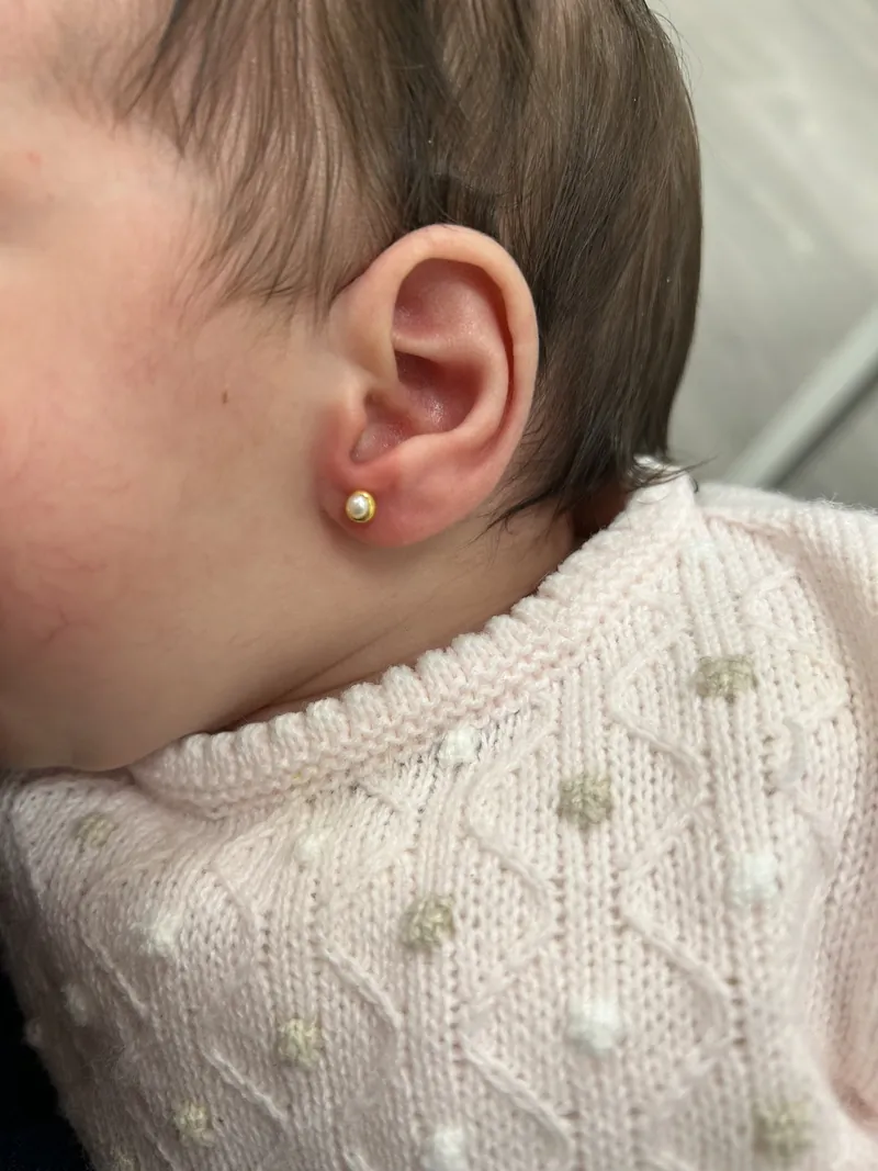 Bebé con pendientes de oro recién puestos